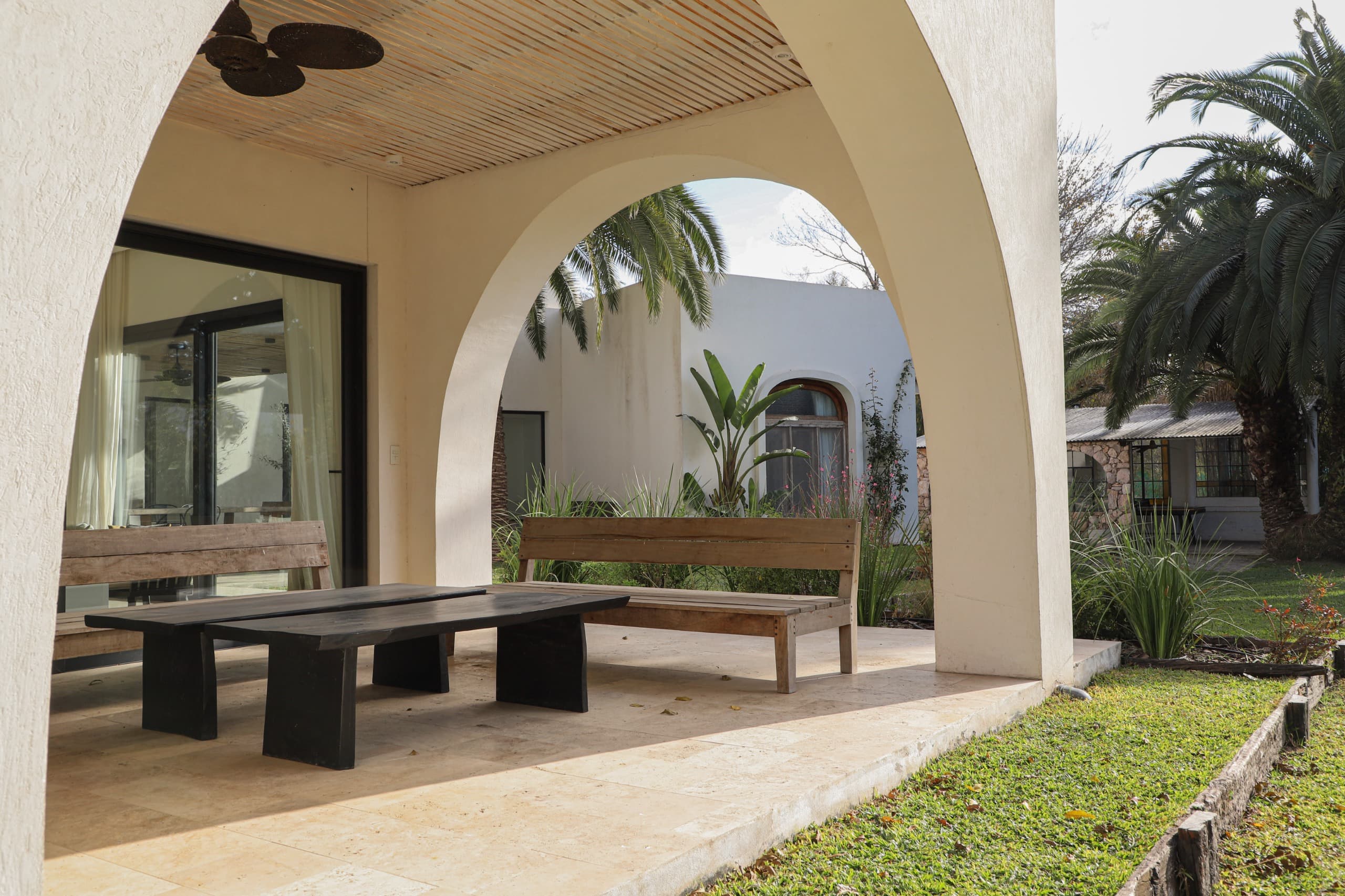Covered outdoor dining area with wooden furniture and garden views